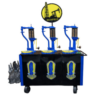 Richfield-Bennett Triple Tank Lubester Cart. 67”x47”x18”. Beautifully restored and outstanding in black, bright blue and yellow. Three 15-galllon tanks with individual lids in yellow with Richfield logo. Three Richfield logos across the front. Mounted on heavy steel caters. Three hand-cranked pumps with sight glasses and large custom Richfield Single-sided sign. Includes a rack of 8 oil bottles with metal pour spouts in basket attached to left side. Absolute statement piece.
