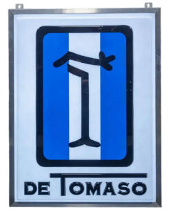 1970s Original De Tomaso Lighted Sign, 48.5”x37”. Metal framed with hanging holes at top. Single-sided white plastic background with blue/white striped De Tomaso large in middle, and the word, De Tomaso at the bottom.