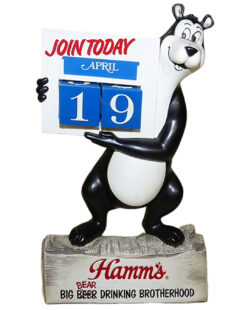 Hamm’s Standing Bear Calendar. A black and white bear is holding a white calendar with “JOIN TODAY” at the top in red letters, followed by the month April in blue, with 19 below. Bear is on beige stand with “Hamm’s” written in red followed by “BIG BEER (crossed out) BEAR DRINIKING BROTHERHOOD” written below in black letters.