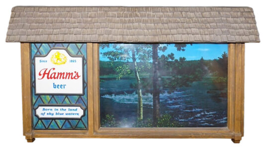 Hamm’s Scene-a-Rama Motion Sign – nice original! Rectangular sign with brown hood framed by wooden panels. The left side contains stained glass design with “Hamm’s beer” written in red and black letters and “Since 1965” at the top. Below this in black letters is the phrase “Born in the land of sky blue waters” next to a scene of woods and a lake on the right.